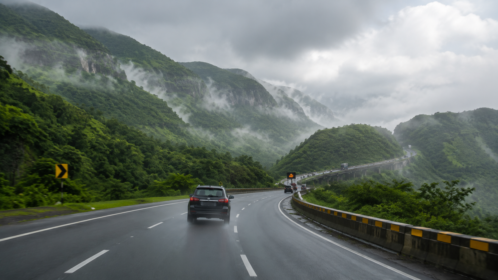 Car driving along the misty Mumbai-Pune Expressway ghat section with green Sahyadri hills on both sides