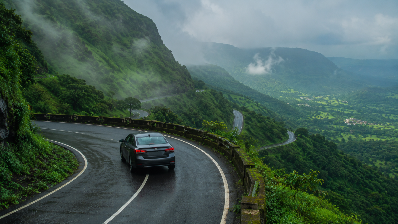 Car driving along a misty ghat road on the Mumbai to Mahabaleshwar route with green Sahyadri hills on both sides