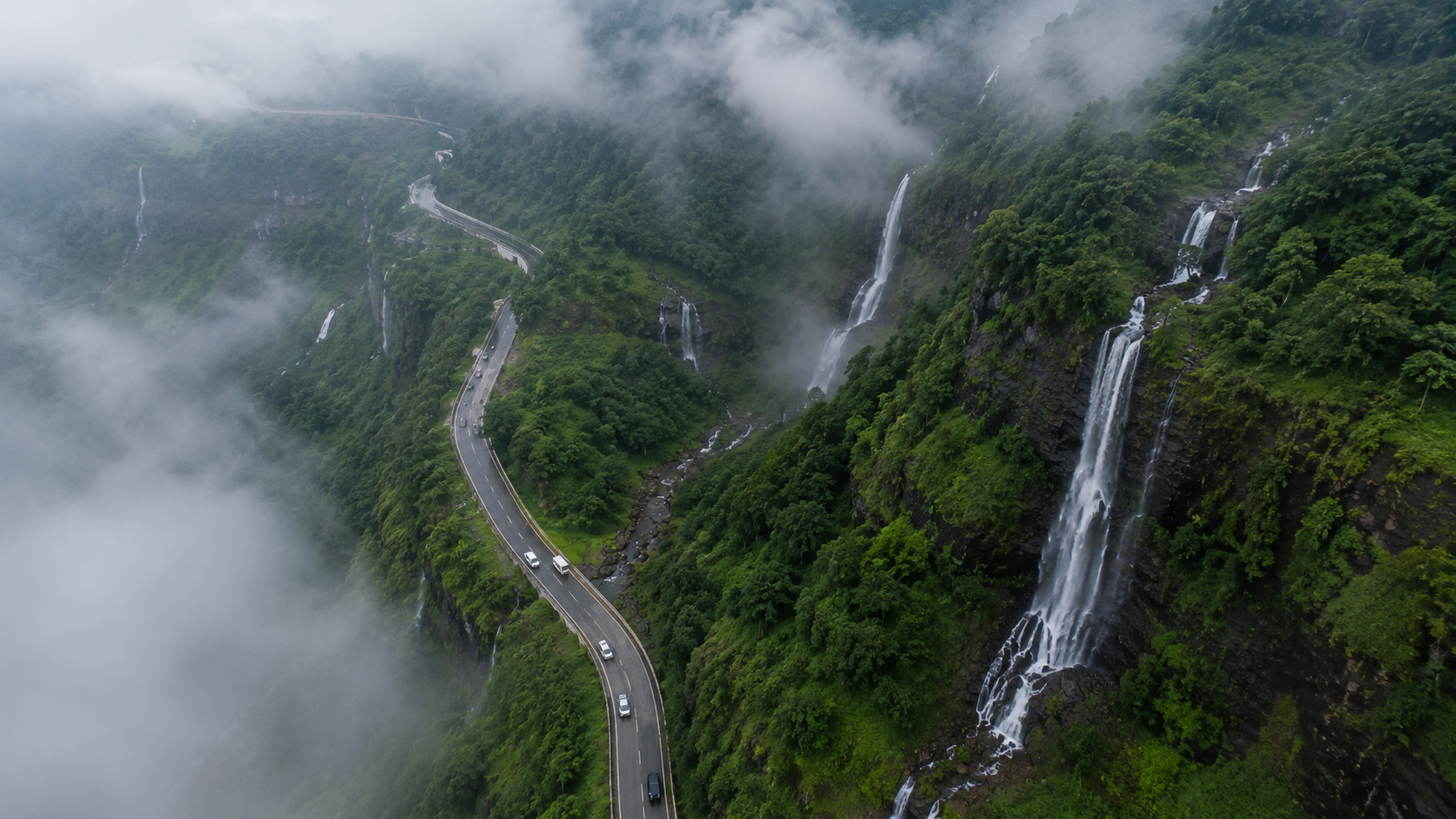 Aerial drone view of multiple waterfalls cascading down the green hills along the Malshej Ghat road