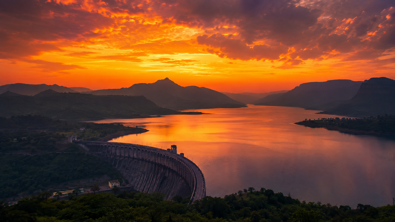 Orange sunset sky reflecting over Wilson Dam and Arthur Lake near Bhandardara