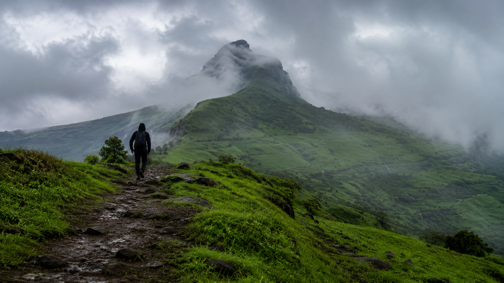 Hiker's silhouette on the misty trail up Kalsubai Peak near Bhandardara