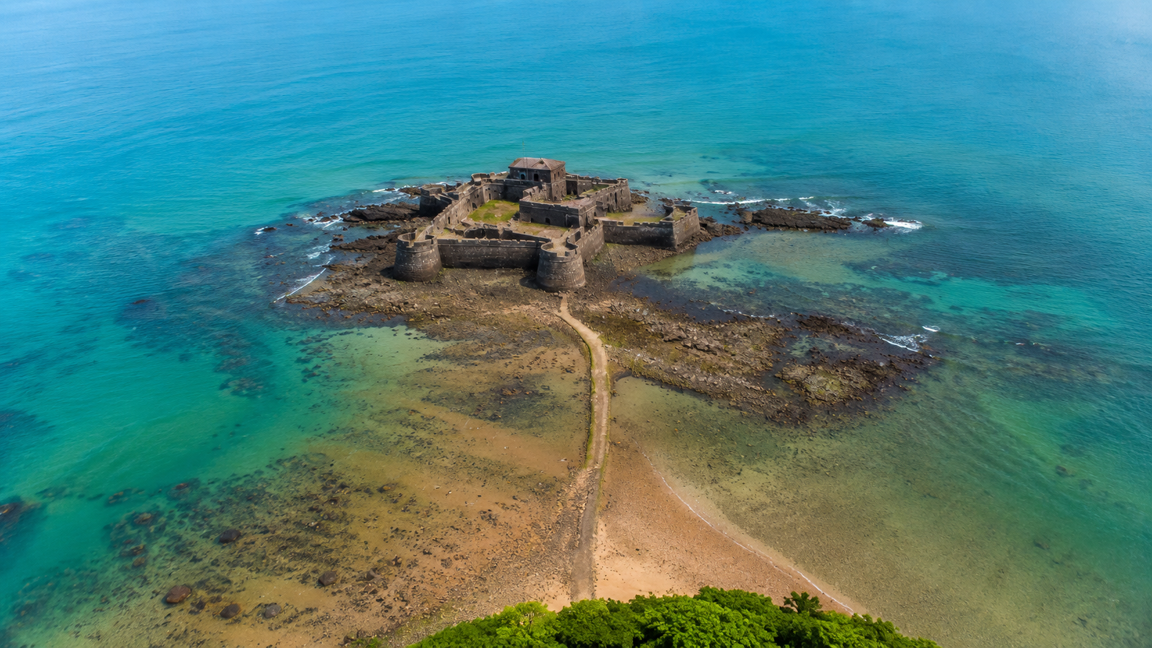 Aerial drone view of Kolaba Fort connected to the Alibaug shoreline by a sandbar at low tide