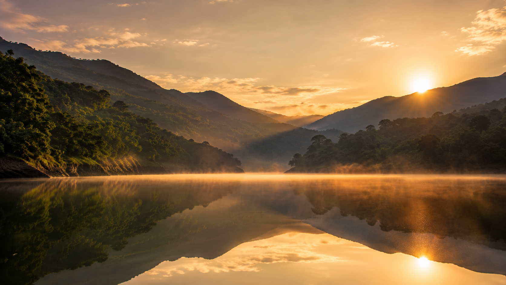 Golden sunrise light over the still waters of Pawna Lake with hills in the background